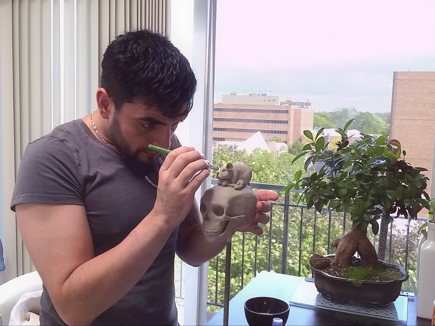 A photo of Sebastian ChicagoSeb Izquierdo sculpting a hamster on a human skull in ceramic clay.